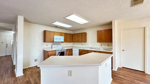 a kitchen with stainless steel appliances granite countertop a refrigerator a sink dishwasher a stove with wooden floor and cabinets