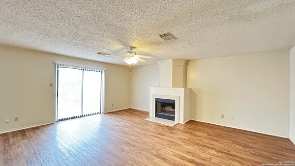 an empty room with wooden floor fireplace and windows