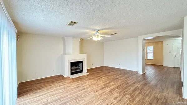 a view of an empty room with wooden floor fireplace and a window