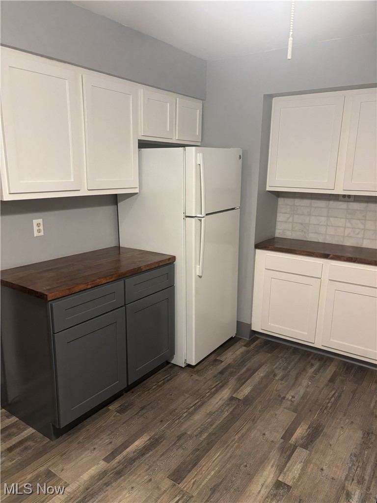 1019 Quilliams Road Cleveland Heights, OH 44121 - Photo 13 of 32 Two tone kitchen featuring wooden counters, freestanding refrigerator, tasteful backsplash, dark wood-style flooring, and dual tone cabinetry