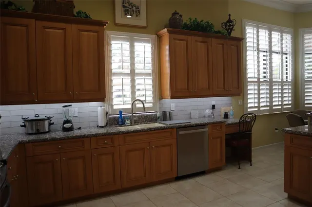 a kitchen with stainless steel appliances granite countertop a sink dishwasher a refrigerator and cabinets with wooden floor