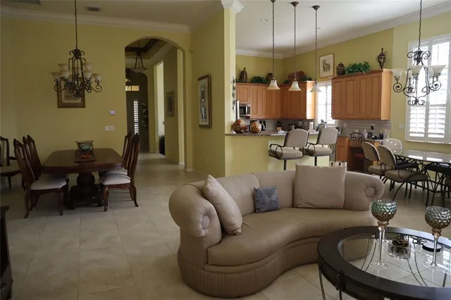 a living room with furniture kitchen view and a chandelier