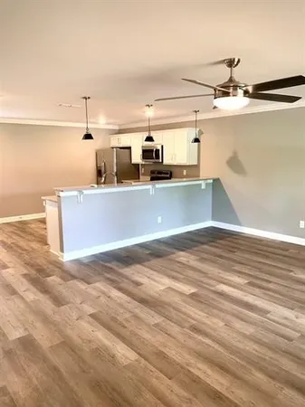a view of a kitchen with kitchen island a sink wooden floor and black appliances