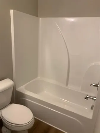 a white toilet sitting next to a bath tub