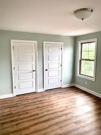 an empty room with wooden floor closet and windows