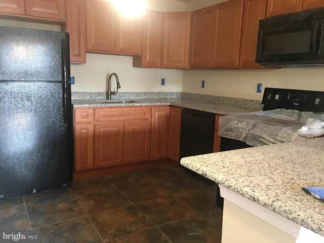 a kitchen with granite countertop a sink a stove and a microwave