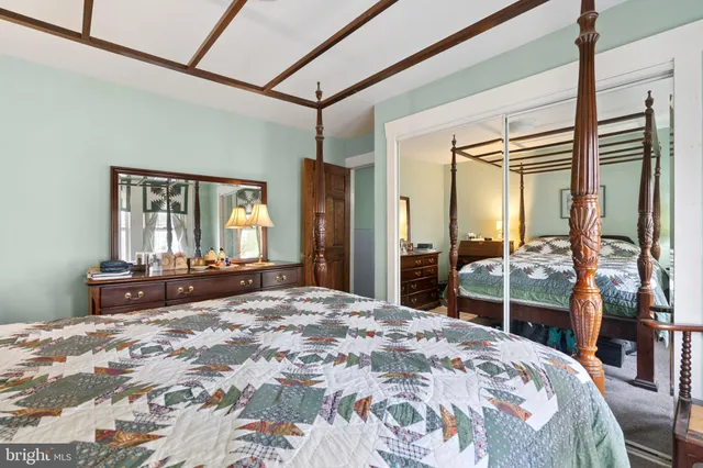 a bedroom with a bed and a large mirror on the dresser