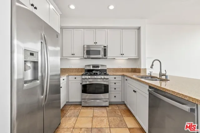 a kitchen with stainless steel appliances granite countertop a stove a refrigerator and a sink