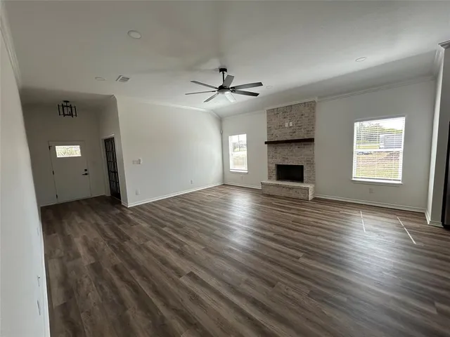 an empty room with wooden floor ceiling fan and windows