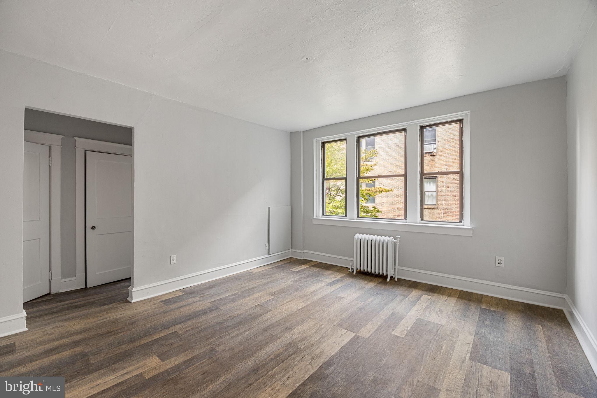 0 Garrett Road, Unit E201 Upper Darby, PA 19082 - Photo 7 of 19 an empty room with wooden floor and windows