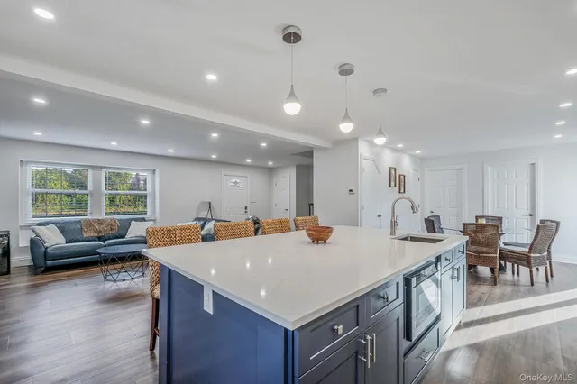 a open kitchen with stainless steel appliances granite countertop a table chairs and a refrigerator
