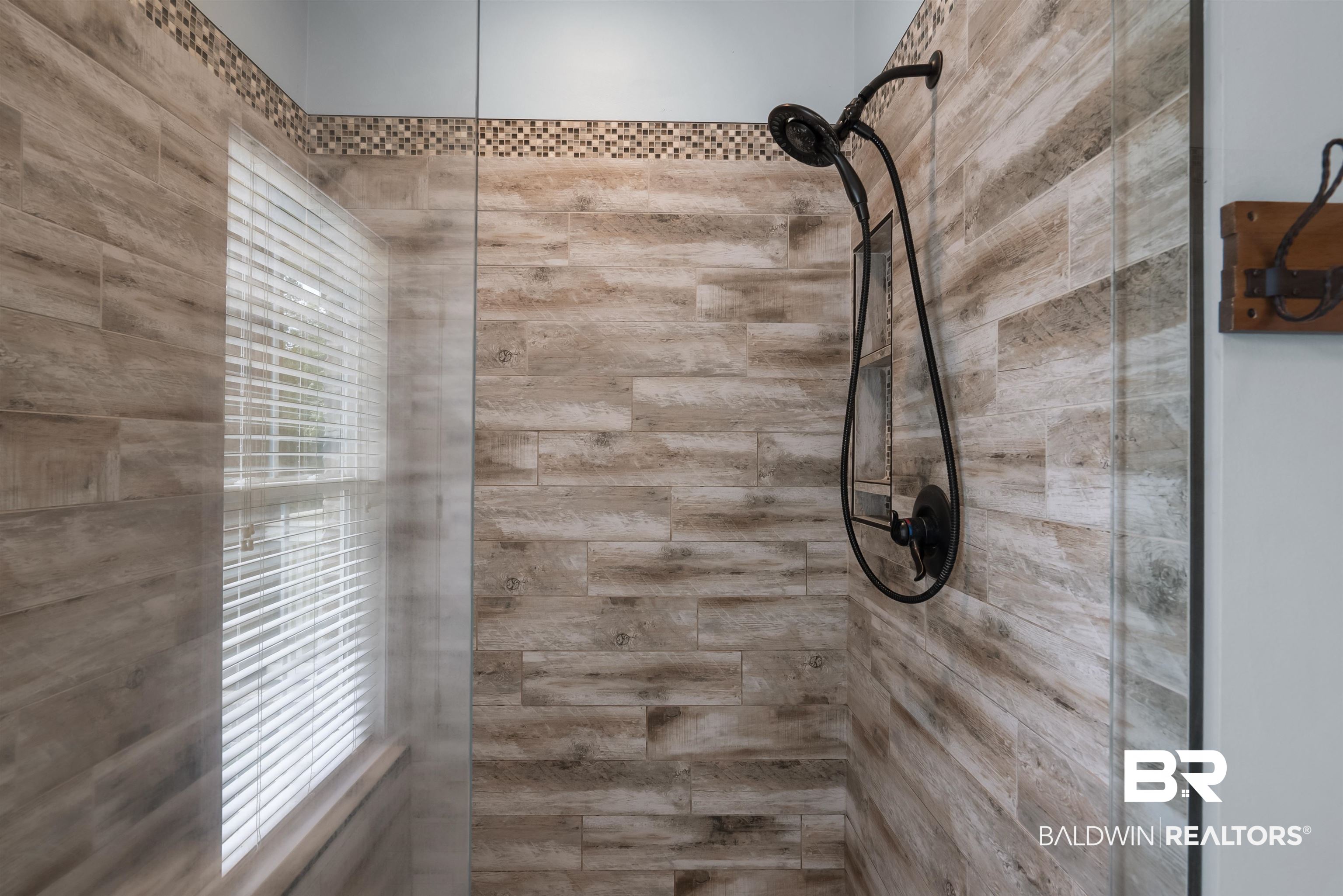 12070 Comalander Road Fairhope, AL 36532 - Photo 25 of 50 Walk-in shower featuring wood-finish tile, clear glass enclosure, matte black shower fixtures, and a decorative mosaic border tile