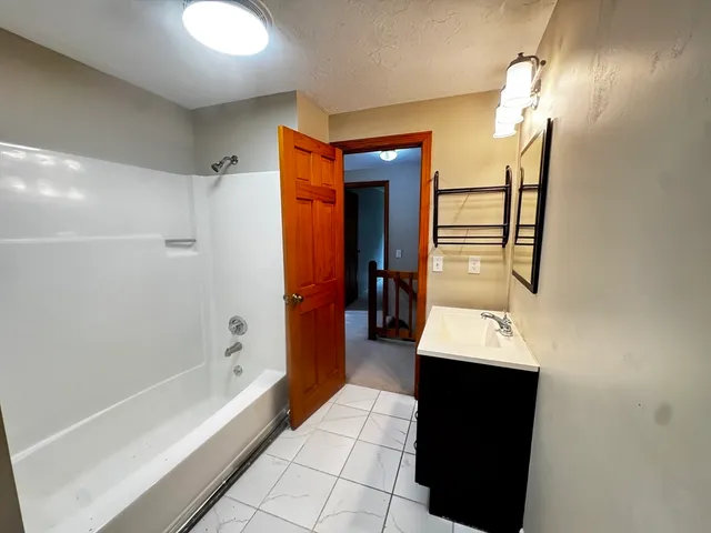 a hallway with white cabinets and black appliances