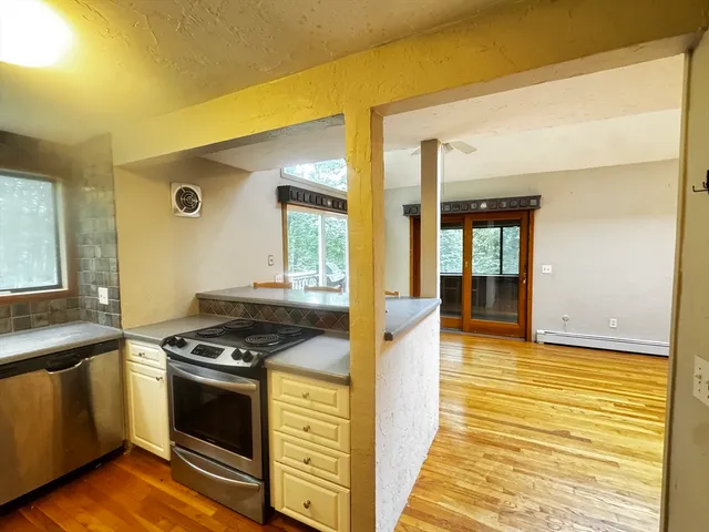 a kitchen with stainless steel appliances granite countertop a stove and a view of living room