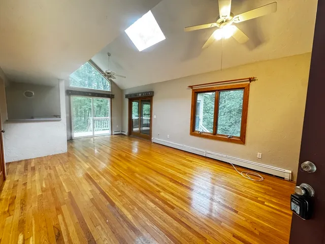 a view of an empty room with a window and wooden floor
