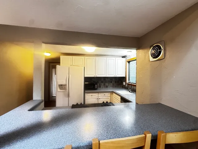 a view of a kitchen with a fridge and a car parked in it