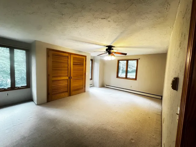 an empty room with chandelier fan and windows