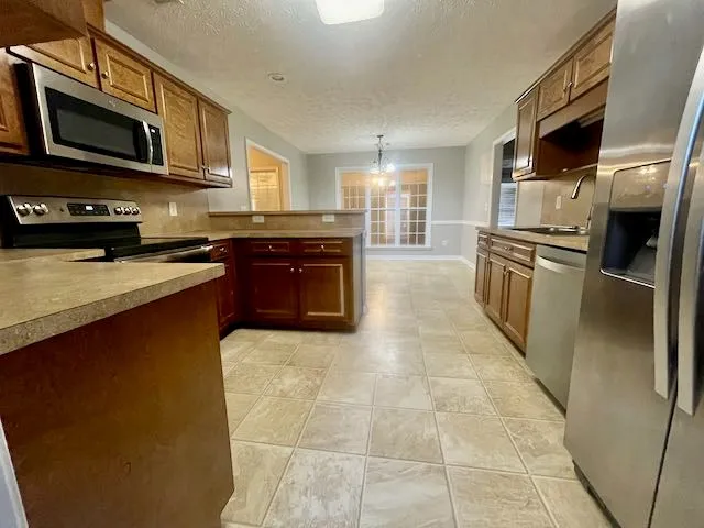 a large kitchen with stainless steel appliances granite countertop a stove refrigerator and a microwave