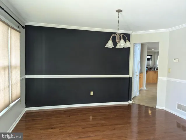 a view of an empty room with wooden floor and windows