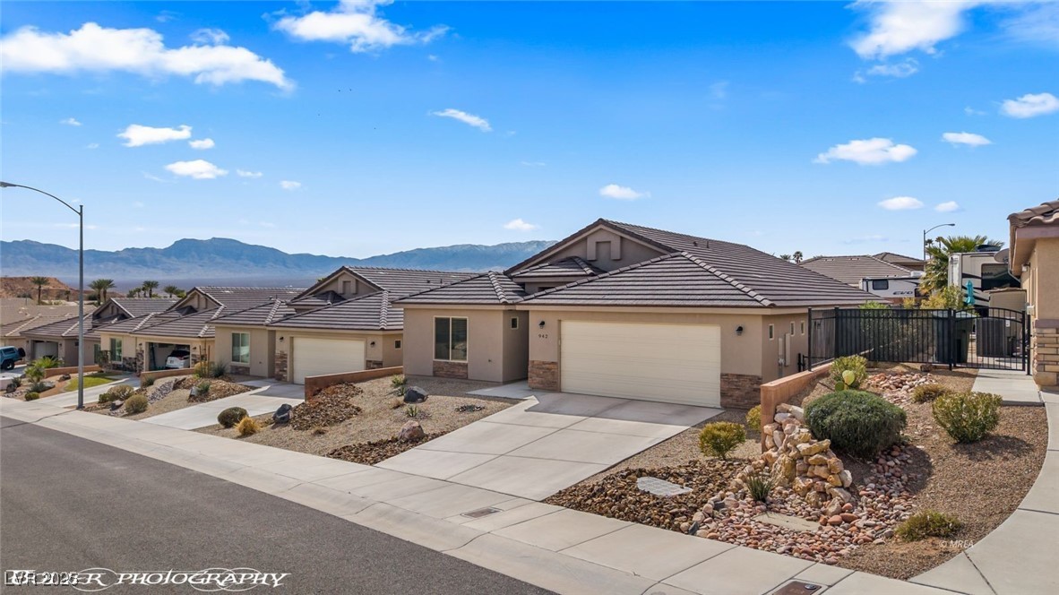 942 Shadow Hawk Ridge Mesquite, NV 89027 - Photo 59 of 67 Ranch-style home featuring a mountain view, stucco siding, fence, a garage, and driveway