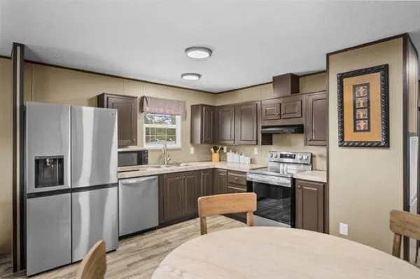 a kitchen with stainless steel appliances a refrigerator a stove a sink and white cabinets with wooden floor