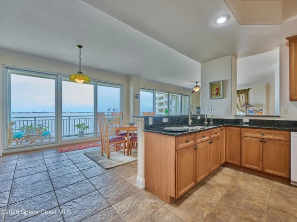 a view of a dining room and livingroom with furniture wooden floor a rug a flat screen tv and a large window