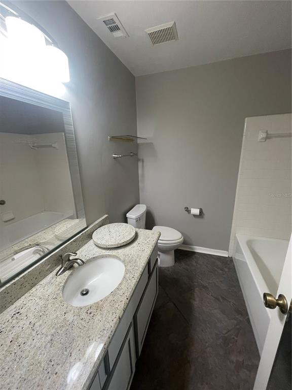 324 Northwest 48th Boulevard, Unit K Gainesville, FL 32607 - Photo 10 of 16 a bathroom with a granite countertop sink a mirror and toilet