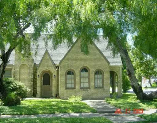 a view of a brick house next to a yard with big trees