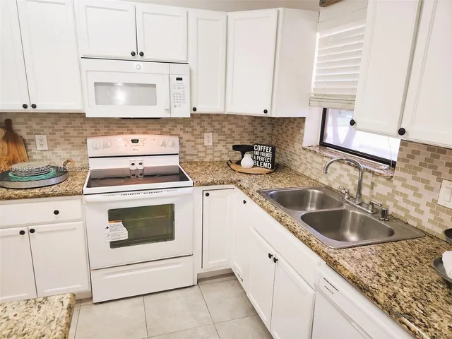 a kitchen with granite countertop white cabinets and white stove