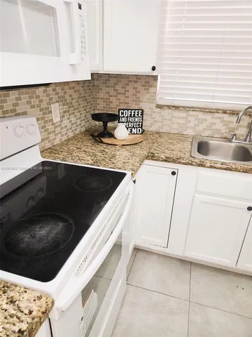a kitchen with granite countertop a sink and a stove