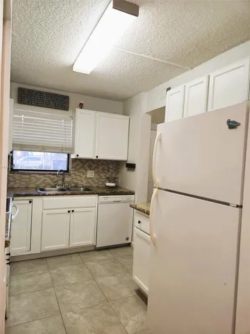 a white refrigerator freezer sitting in a kitchen with white cabinets