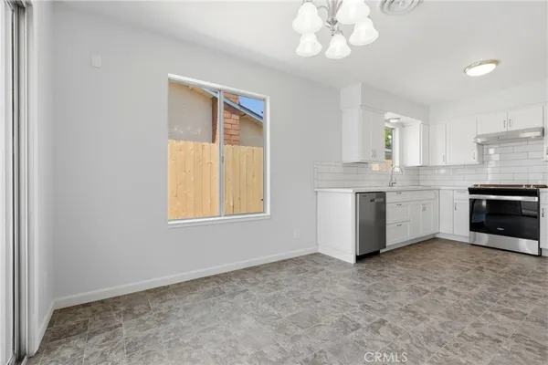 a kitchen with stainless steel appliances granite countertop a stove a sink and a chandelier