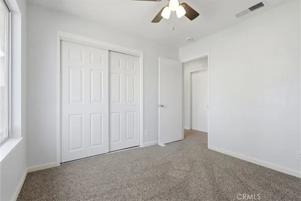 an empty room with a ceiling fan and a window