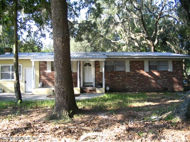 a front view of a house with yard chairs and large tree