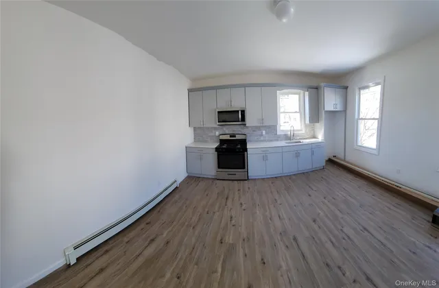 a view of a kitchen with wooden floor and electronic appliances