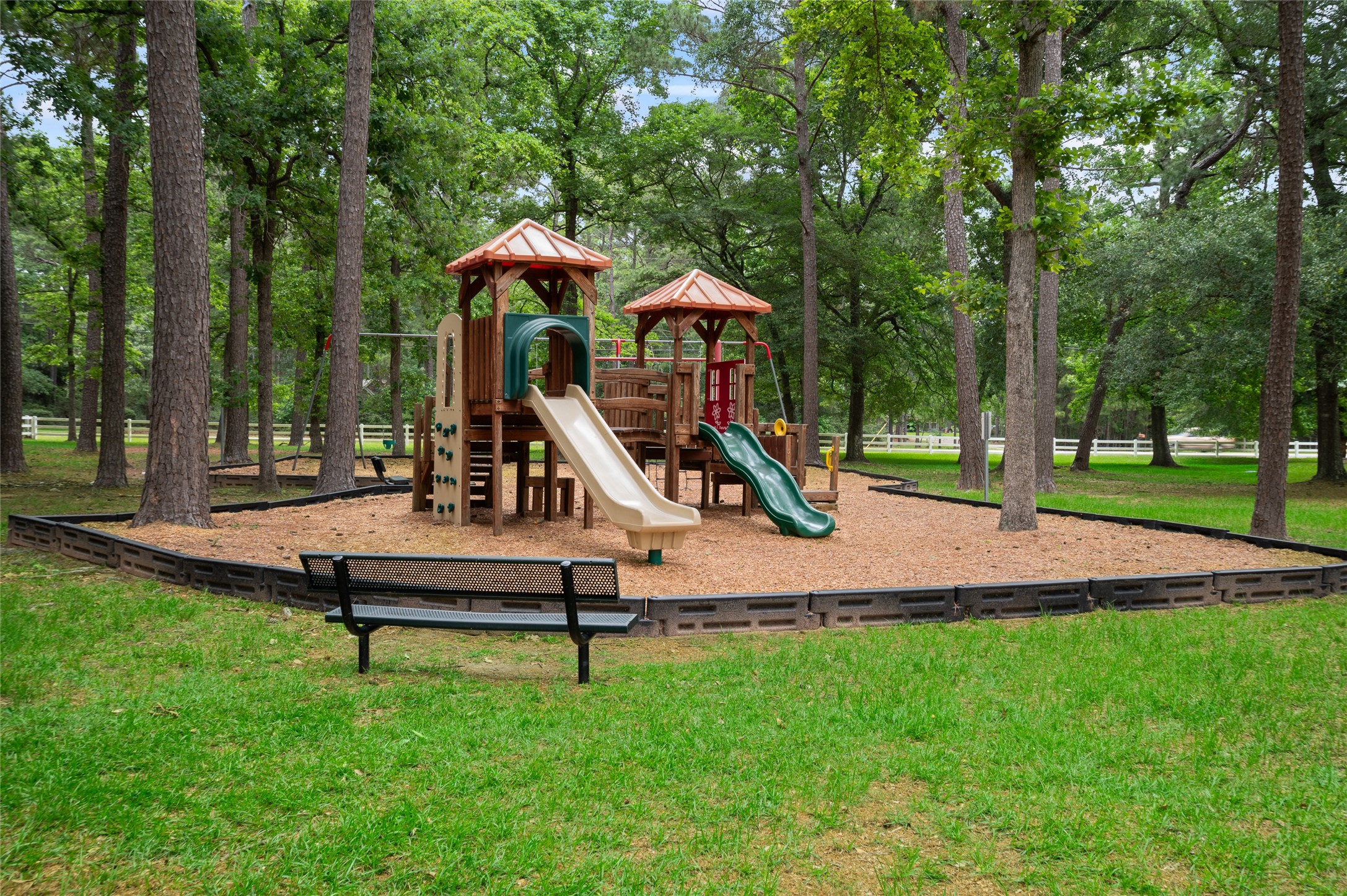 20103 Mahogany Ridge Drive Magnolia, TX 77355 - Photo 41 of 42 This photo features a charming playground set in one of the neighborhood parks. It includes slides, climbing structures, and a bench nearby, offering a recreational space surrounded by nature.