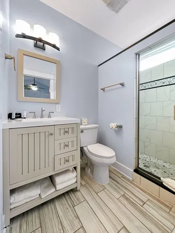 a kitchen with stainless steel appliances a stove top oven a sink a refrigerator white cabinets and wooden floor