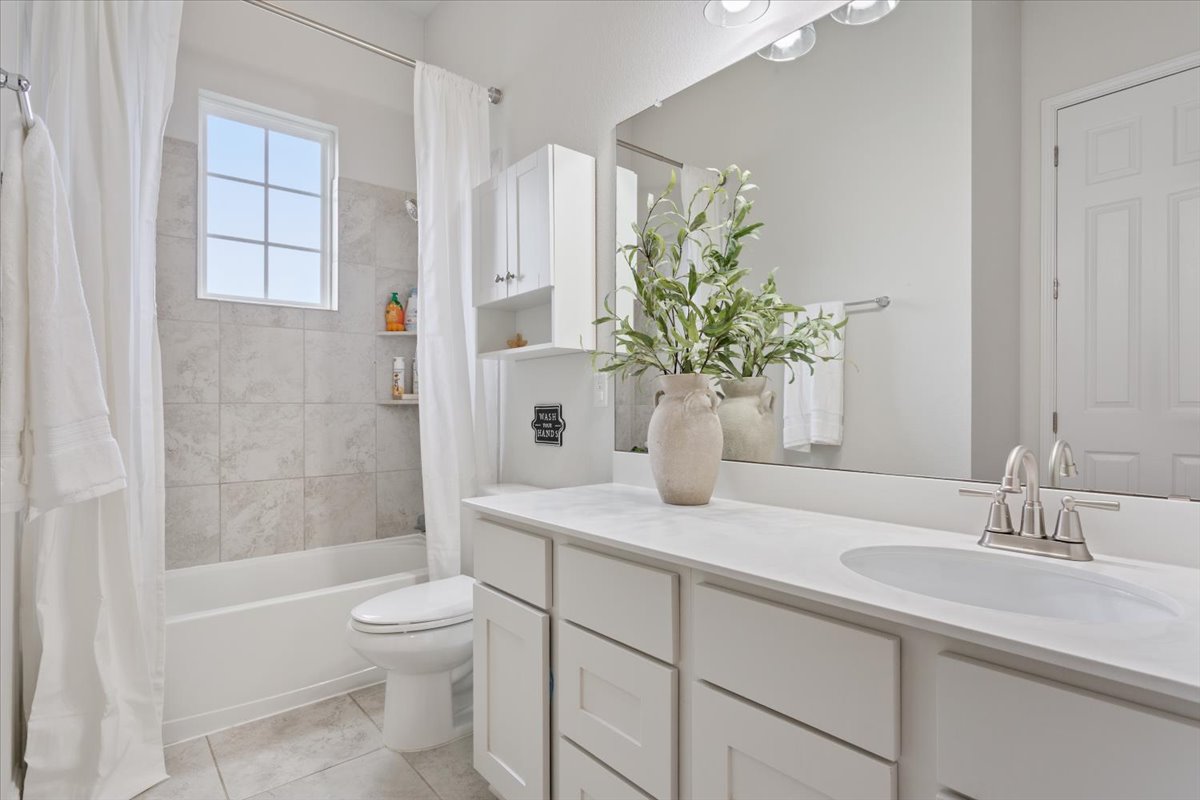 424 Millard Street Georgetown, TX 78628 - Photo 24 of 37 A well-lit bathroom with crisp white cabinetry and a tiled shower-tub combination.
