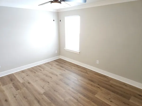 an empty room with wooden floor and windows
