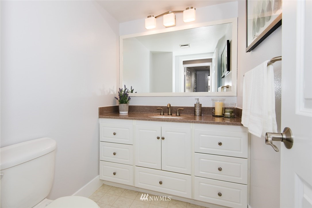 7323 Sand Point Way Northeast, Unit 106 Seattle, WA 98115 - Photo 14 of 21 a bathroom with a granite countertop sink vanity mirror bathtub and toilet