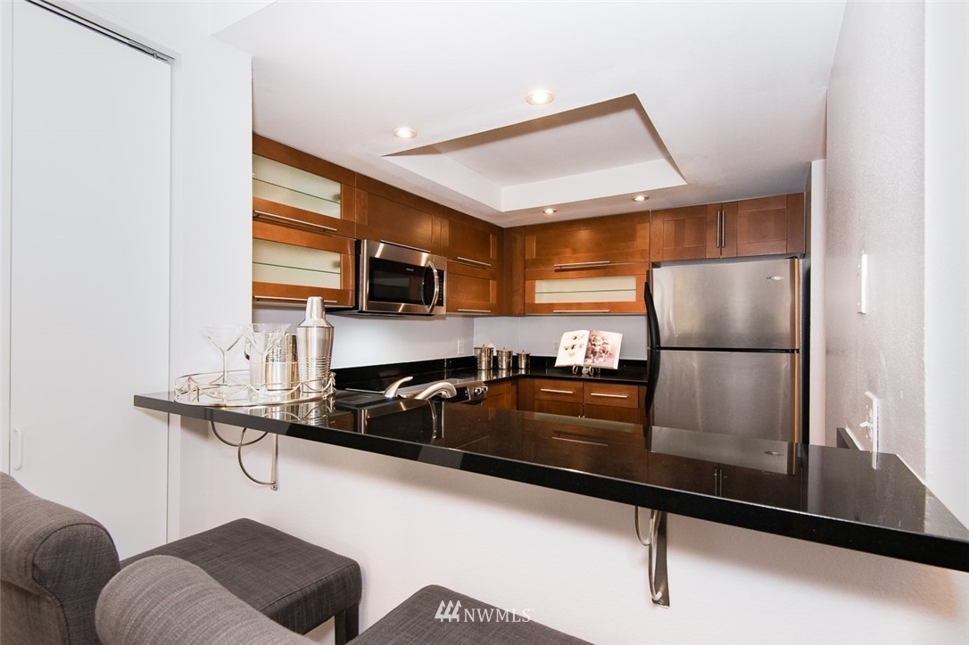 7323 Sand Point Way Northeast, Unit 106 Seattle, WA 98115 - Photo 15 of 21 a kitchen with stainless steel appliances granite countertop a refrigerator a stove and a sink with wooden floor