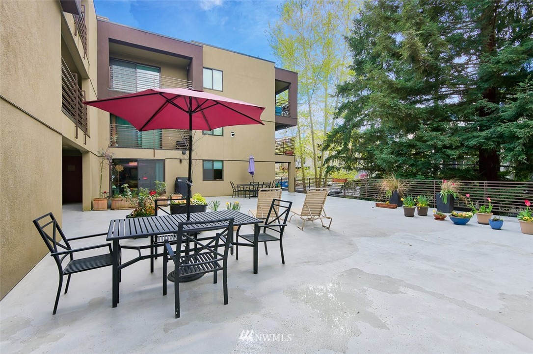 7323 Sand Point Way Northeast, Unit 106 Seattle, WA 98115 - Photo 5 of 21 a view of a patio with dining table and chairs under an umbrella