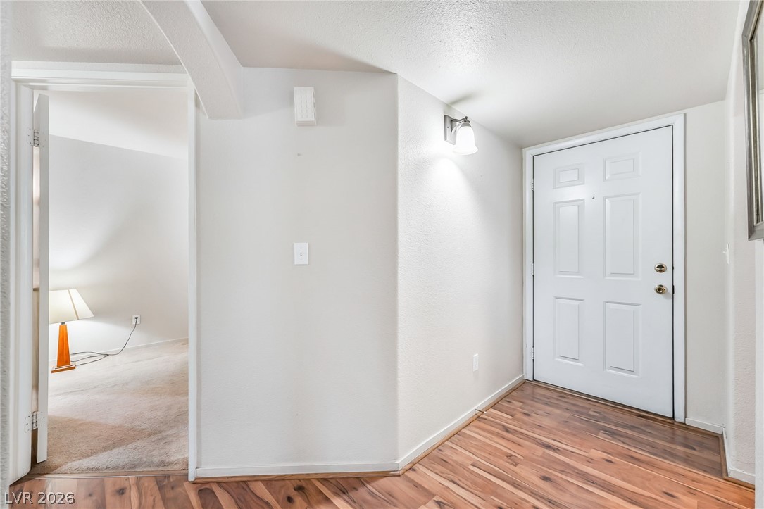698 South Racetrack Road, Unit 1512 Henderson, NV 89015 - Photo 14 of 30 Rich wood-look flooring guides entry past clean architectural lines and an adjoining carpeted room.