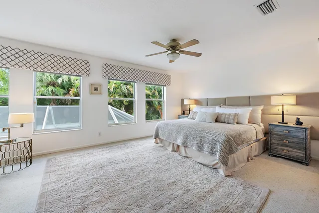 a spacious bedroom with a bed a table and windows