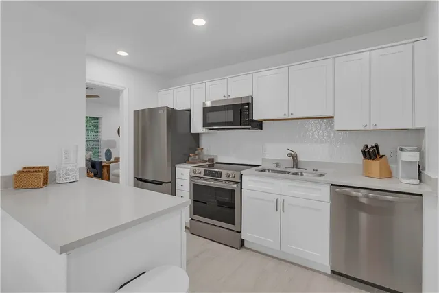 a kitchen with stainless steel appliances granite countertop a sink dishwasher a refrigerator and a dining table with wooden floor