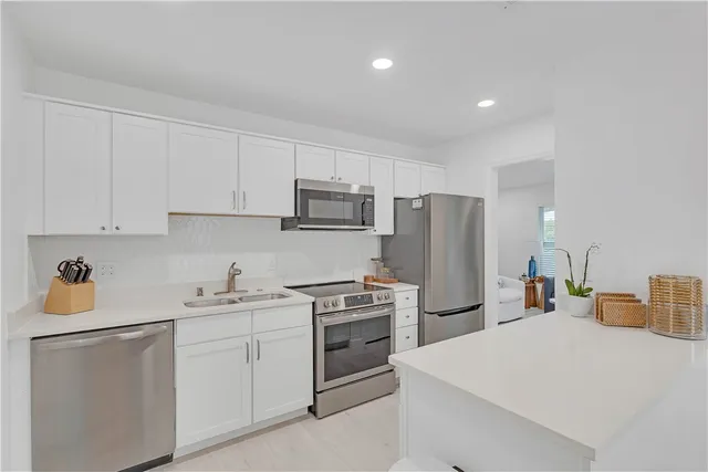 a kitchen with a sink a refrigerator and white cabinets