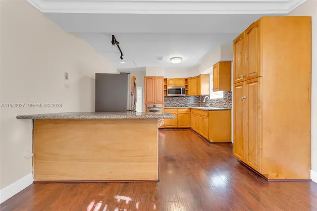 a kitchen with stainless steel appliances granite countertop a refrigerator a oven a sink and wooden floors