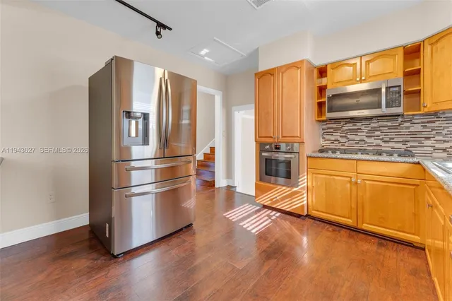 a kitchen with stainless steel appliances granite countertop a refrigerator microwave and wooden floor