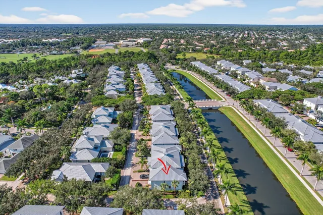 a front view of a house with a garden and palm trees