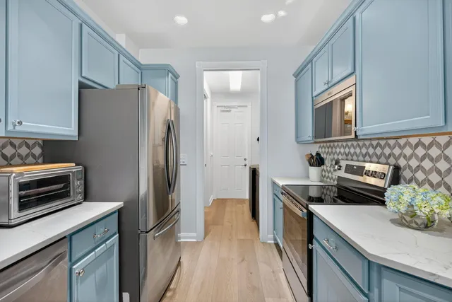 a kitchen with stainless steel appliances kitchen island granite countertop a refrigerator and a stove top oven